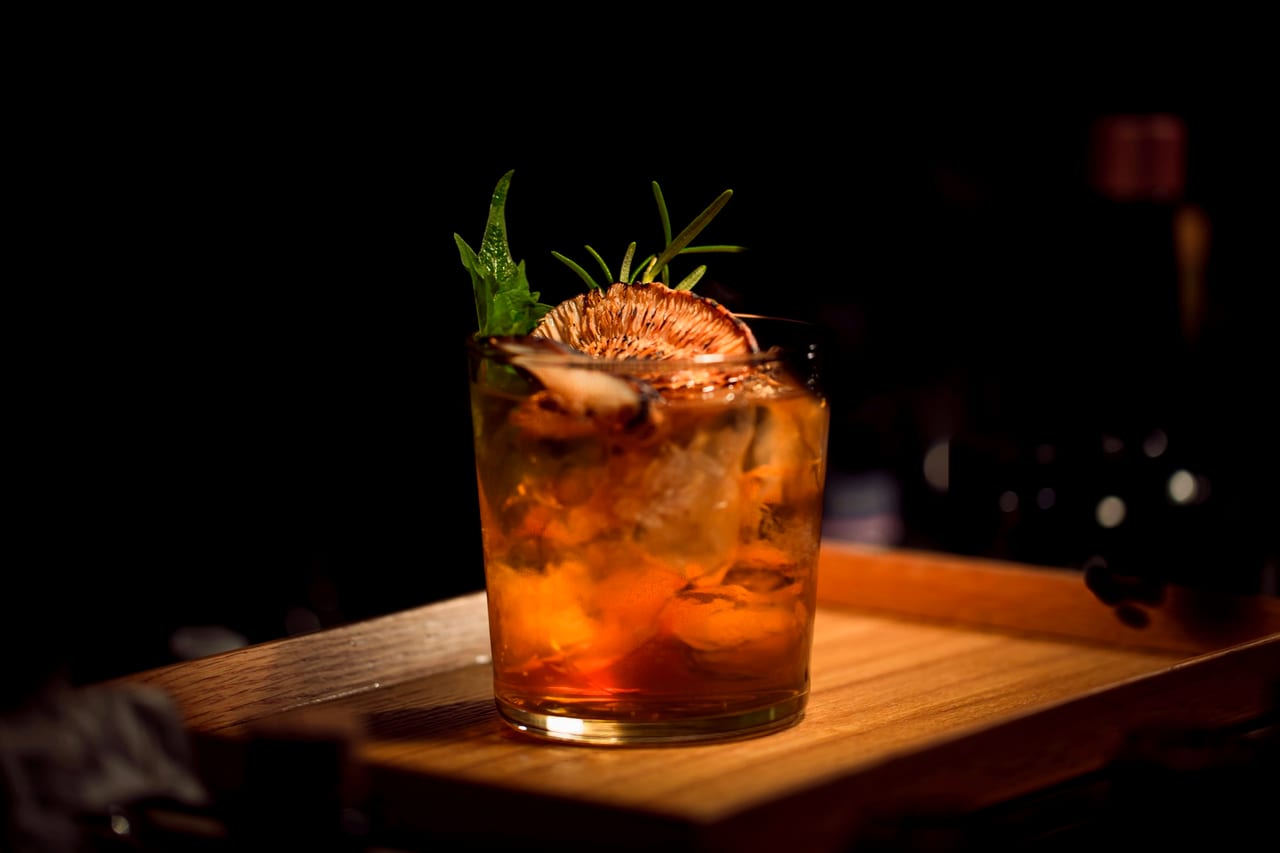 A bartender mixing cocktails behind a busy bar.
