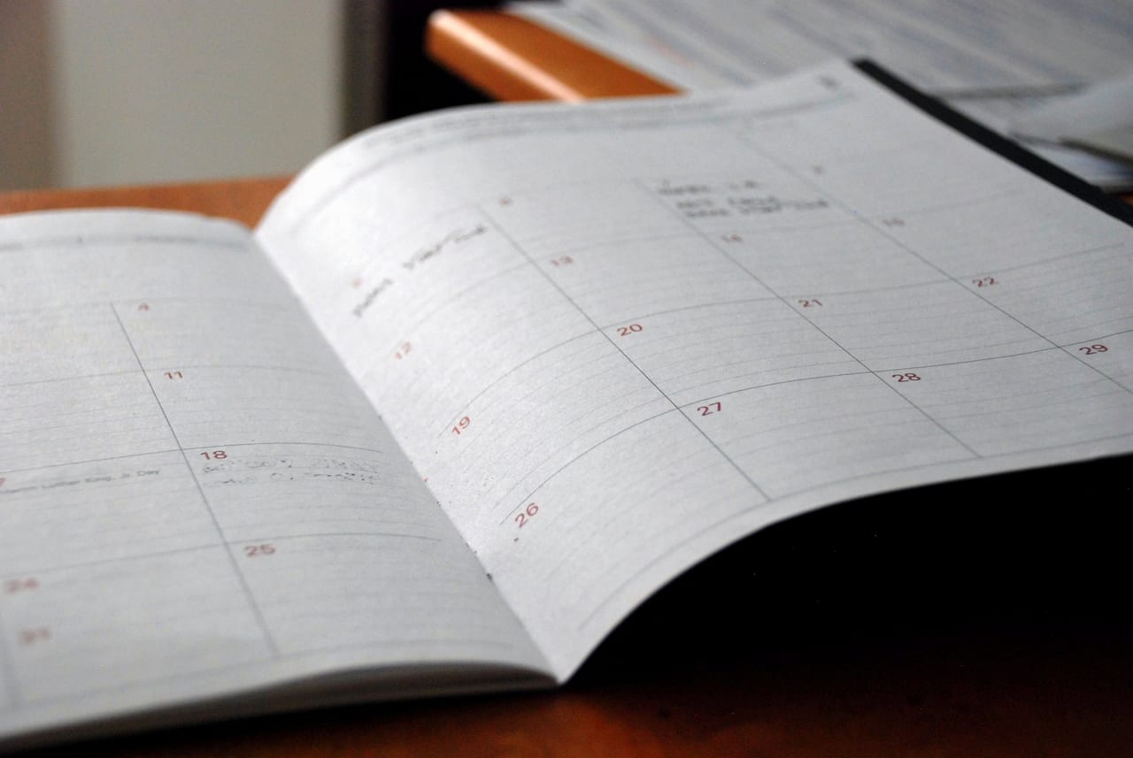 An open planner on a wooden desk — bookings and records.