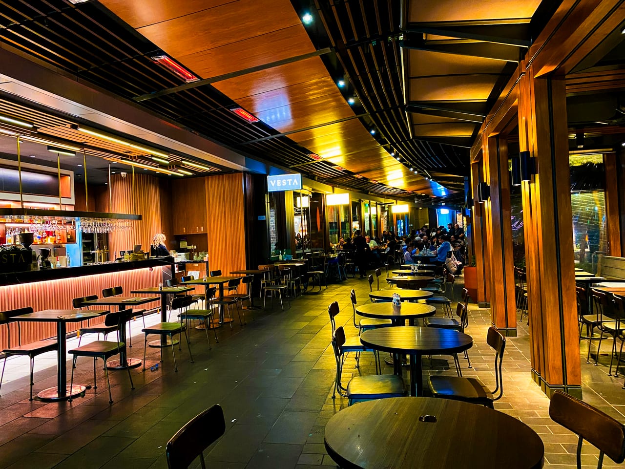 A warm restaurant dining room filled with tables and chairs.
