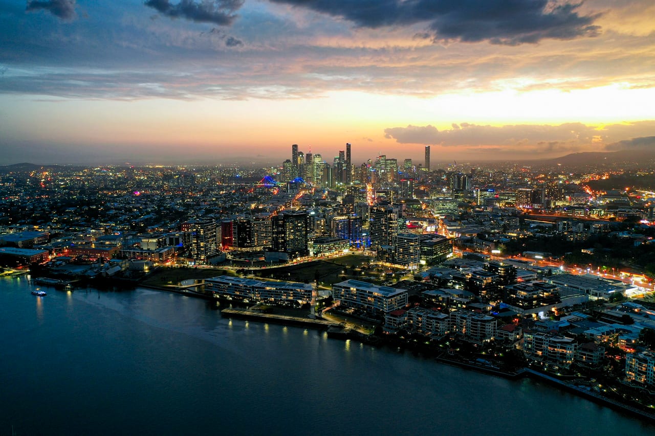 The Brisbane city skyline at dusk, high-rises above the river.