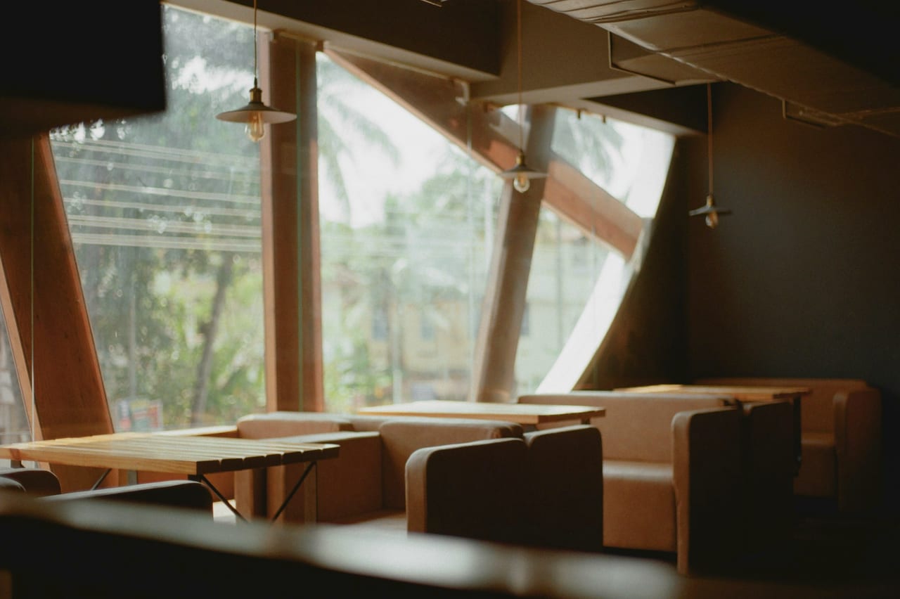 An empty café, tables along a bright window in the morning.
