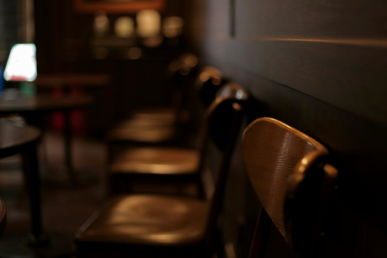 A row of empty chairs in a dim room after close.