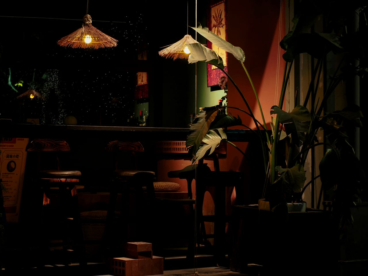 A dimly lit bar interior with stools and plants.