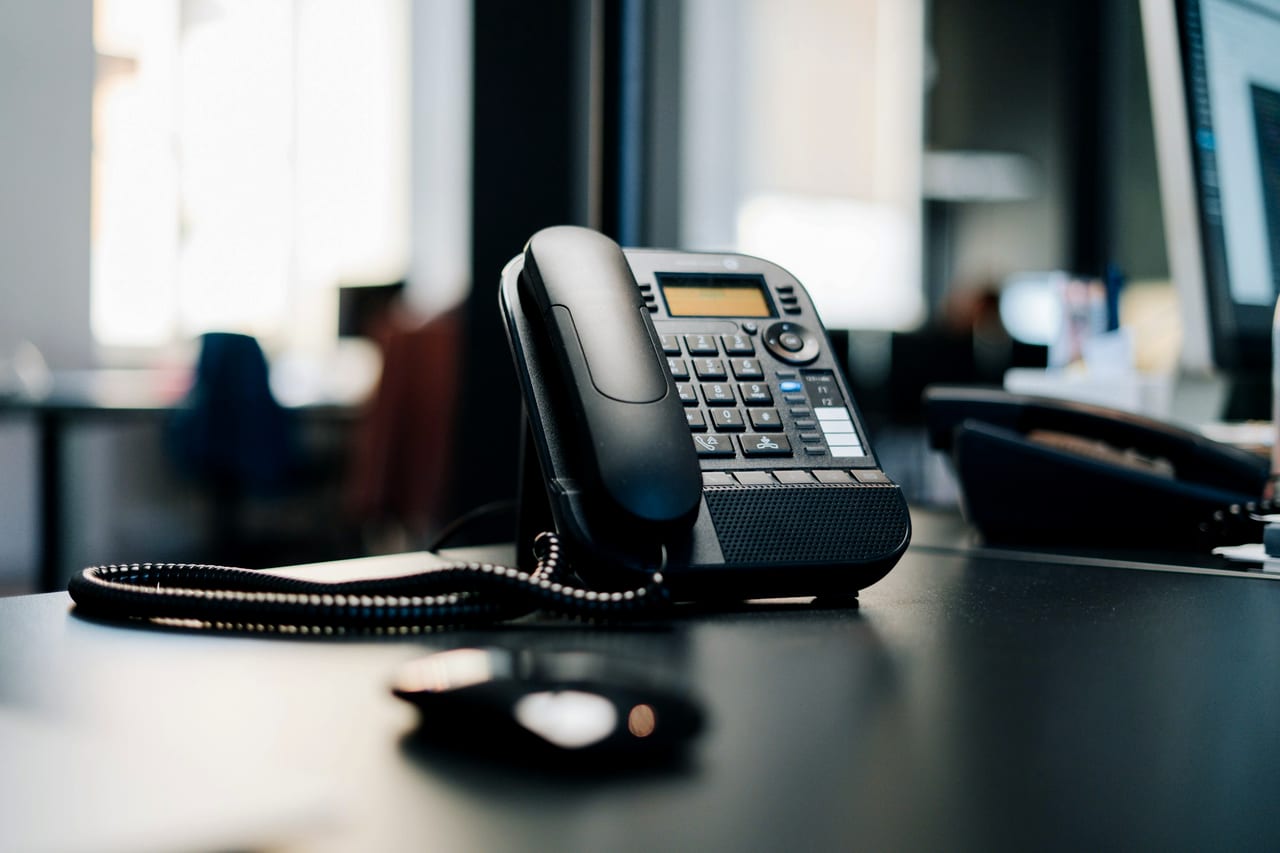 A black desk phone on a dark table