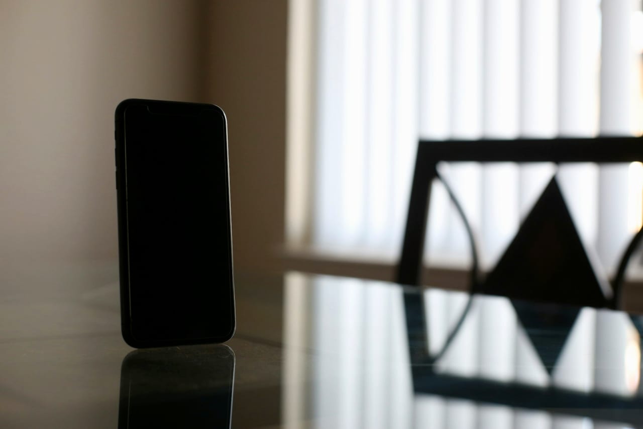 A black smartphone resting on a wooden table