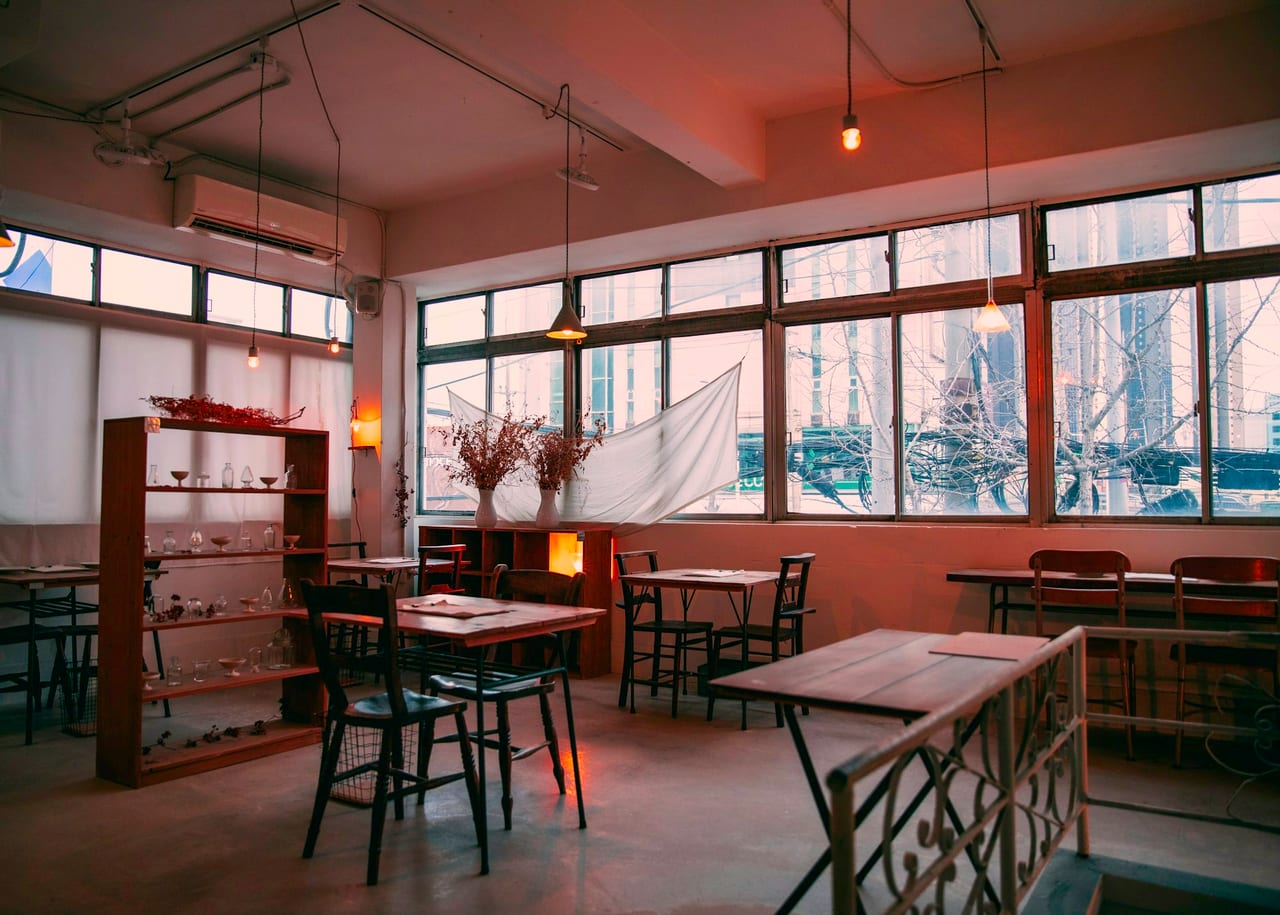 A cosy café interior with large windows and warm light
