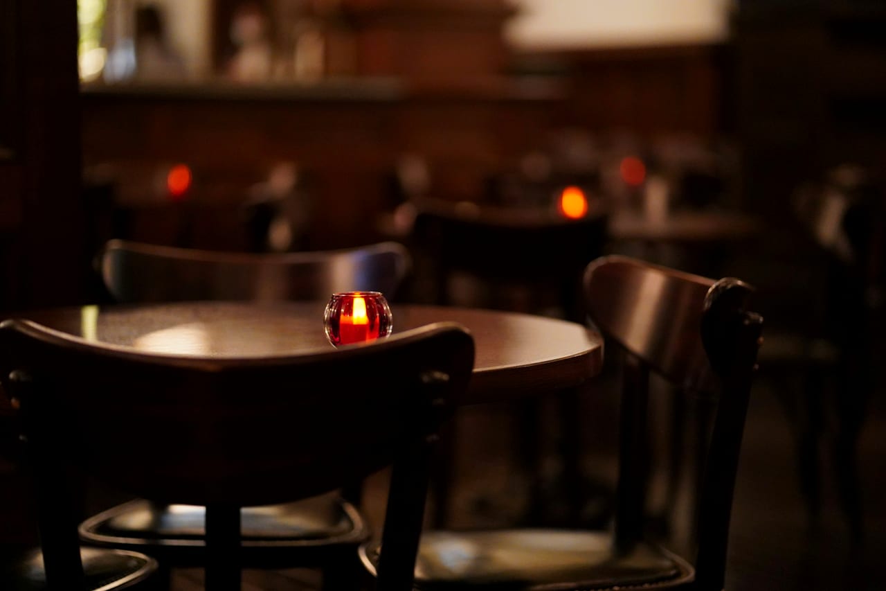 A single candle glowing on a restaurant table.