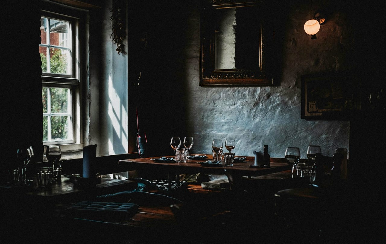 Wine glasses on a table by a window.