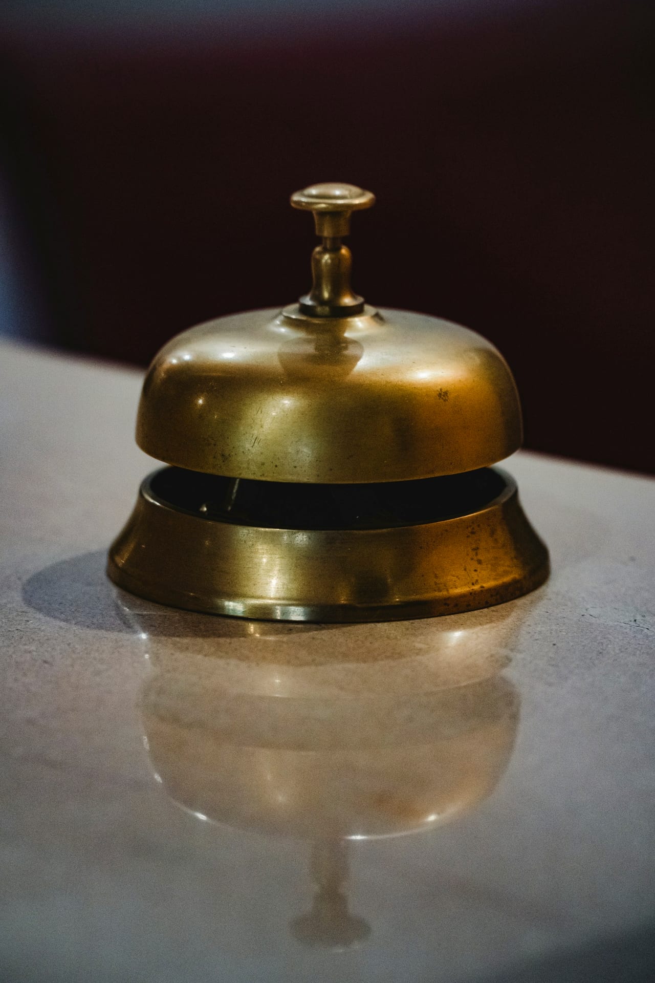 A brass reception bell on a hotel front desk.