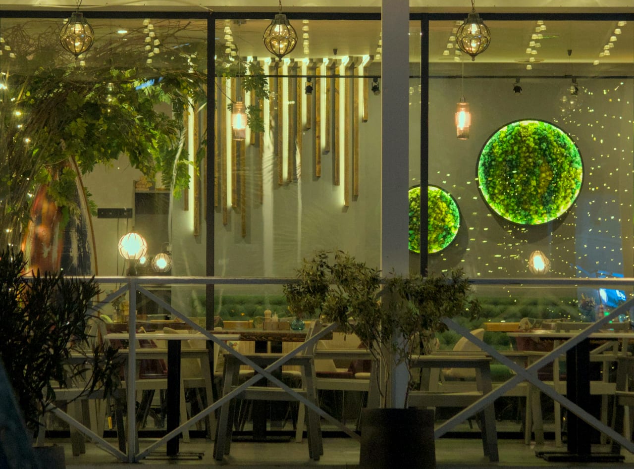 A modern restaurant interior with a green wall and warm light