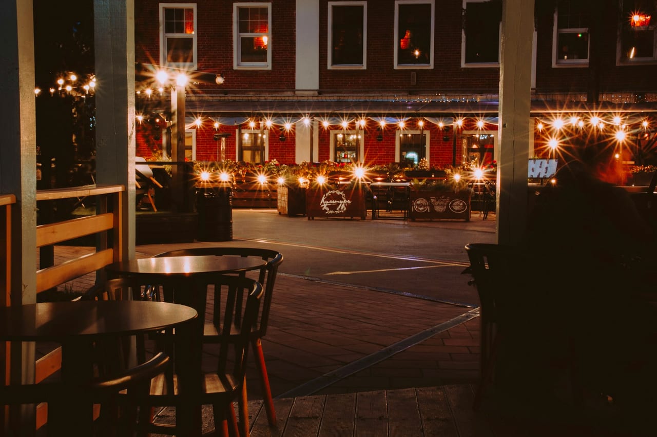 An empty outdoor restaurant terrace at night with string lights