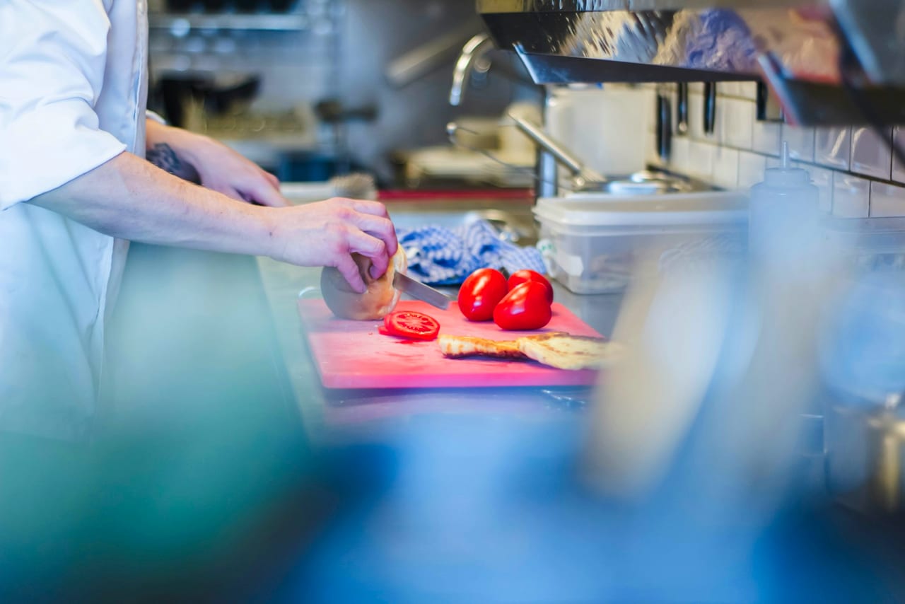 Hands slicing tomatoes on a board, close detail