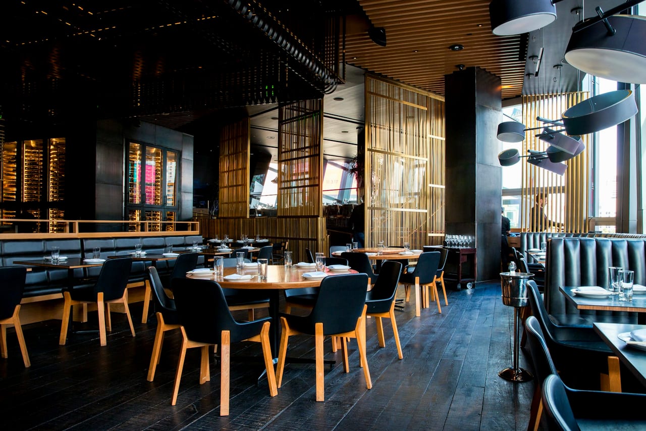 A candlelit restaurant interior in the evening, tables set for service.