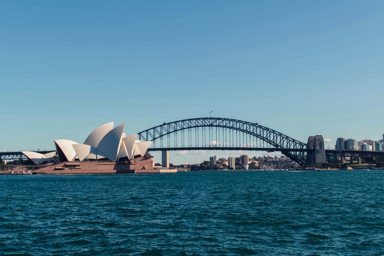 Sydney Harbour at dusk — the Opera House and Harbour Bridge on the water.