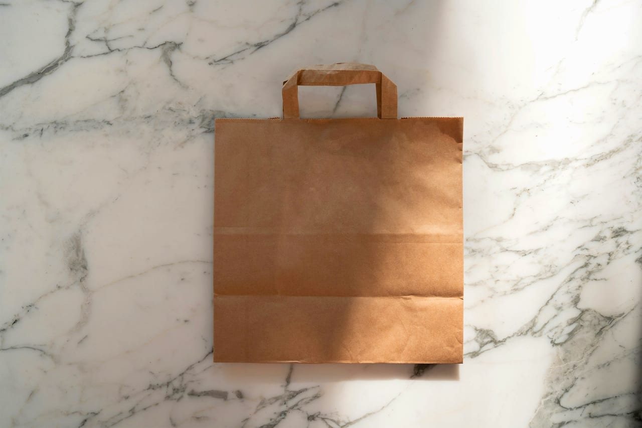 A brown paper takeaway bag on a marble counter.