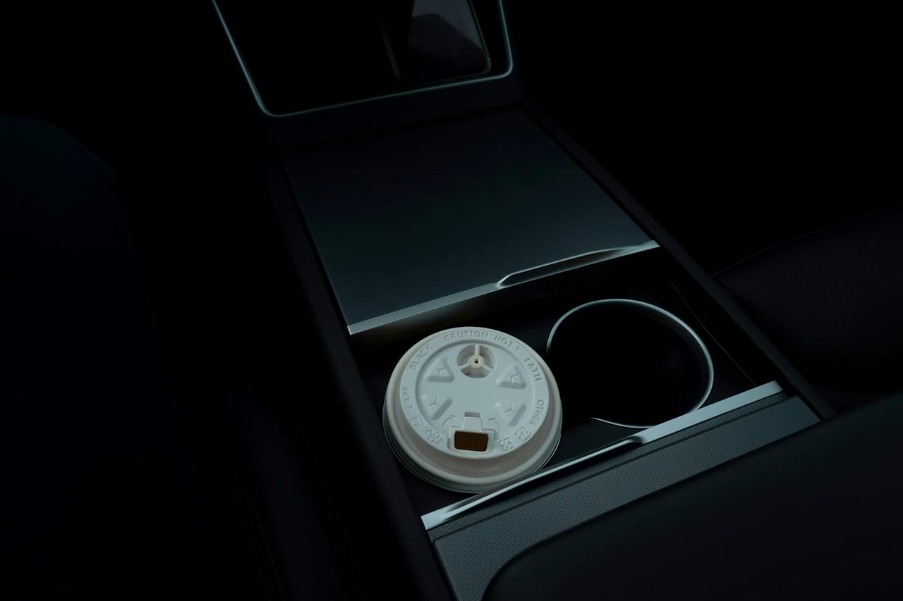 A takeaway coffee cup in a car cup holder.