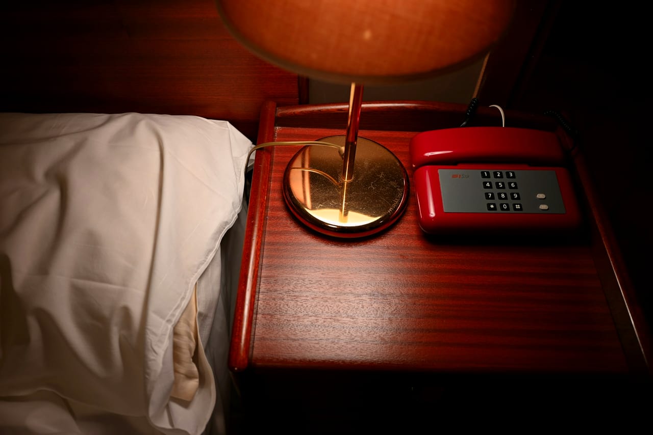 A telephone beside a warm lamp on a wooden table