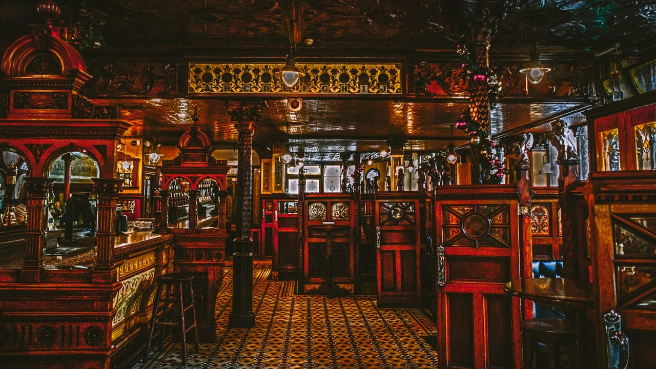 An ornate traditional bar interior in carved mahogany and brass, quiet between services