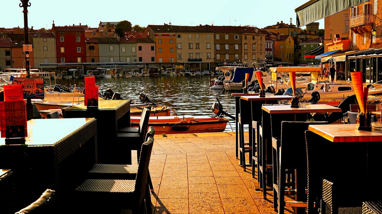Terrasse d'un restaurant au bord d'un vieux port méditerranéen — barques et maisons colorées