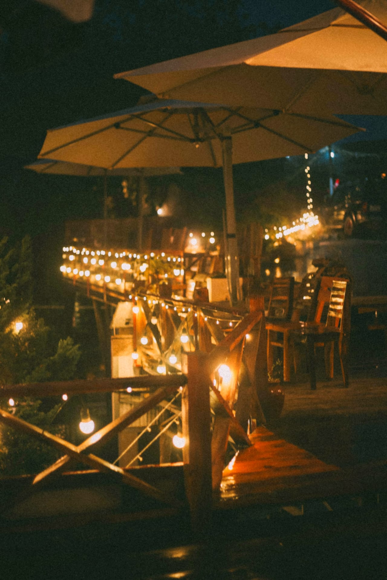Terrasse d'un restaurant le soir dans le sud de la France, parasols et guirlandes lumineuses