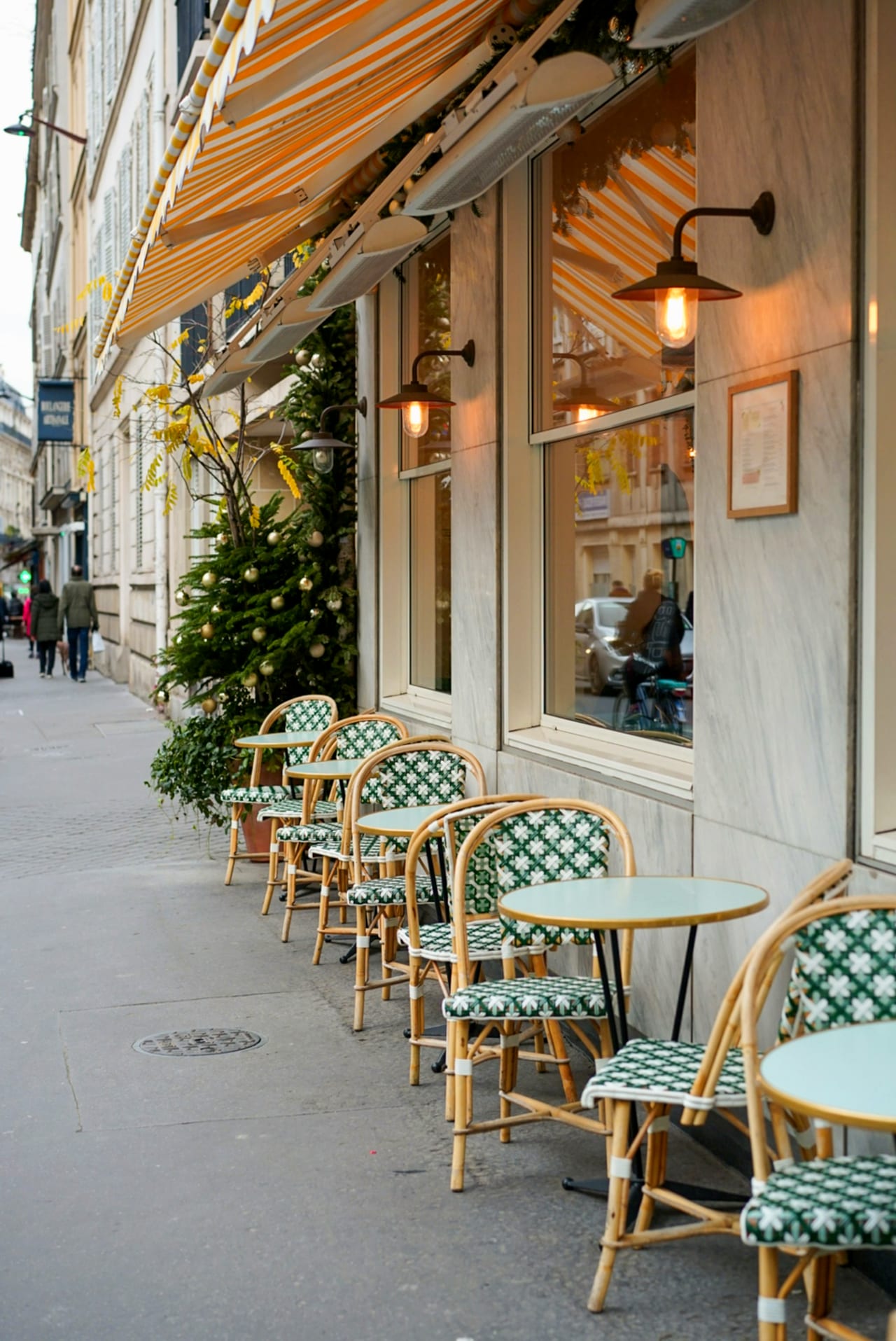 Terrasse de café parisien — store rayé et chaises de bistrot en rotin vert