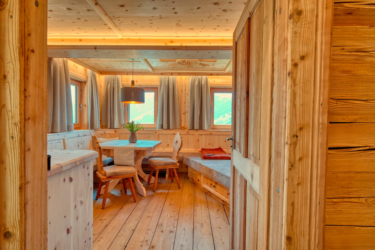Coin d'une winstub alsacienne lambrissée de pin clair, table dressée et banquette