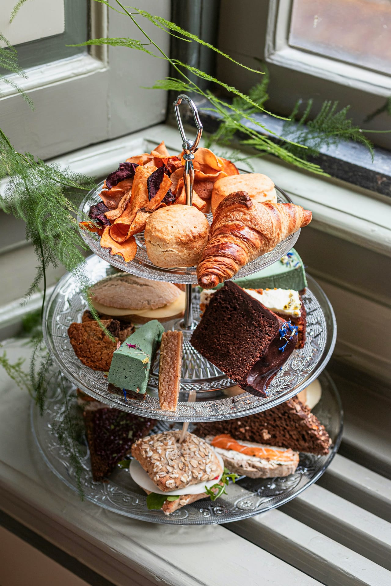 A three-tiered afternoon tea stand of scones, cakes and finger sandwiches