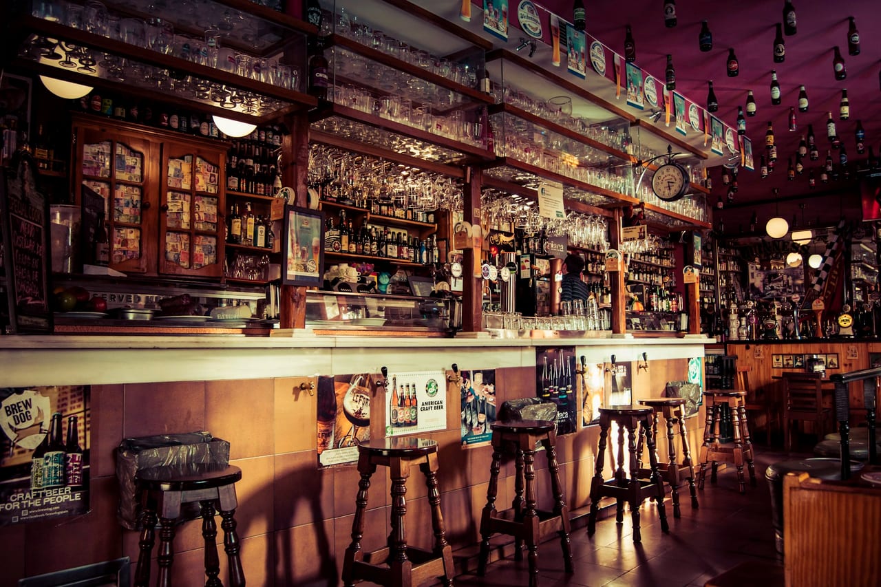 An empty bar with stools and shelves of glassware before service