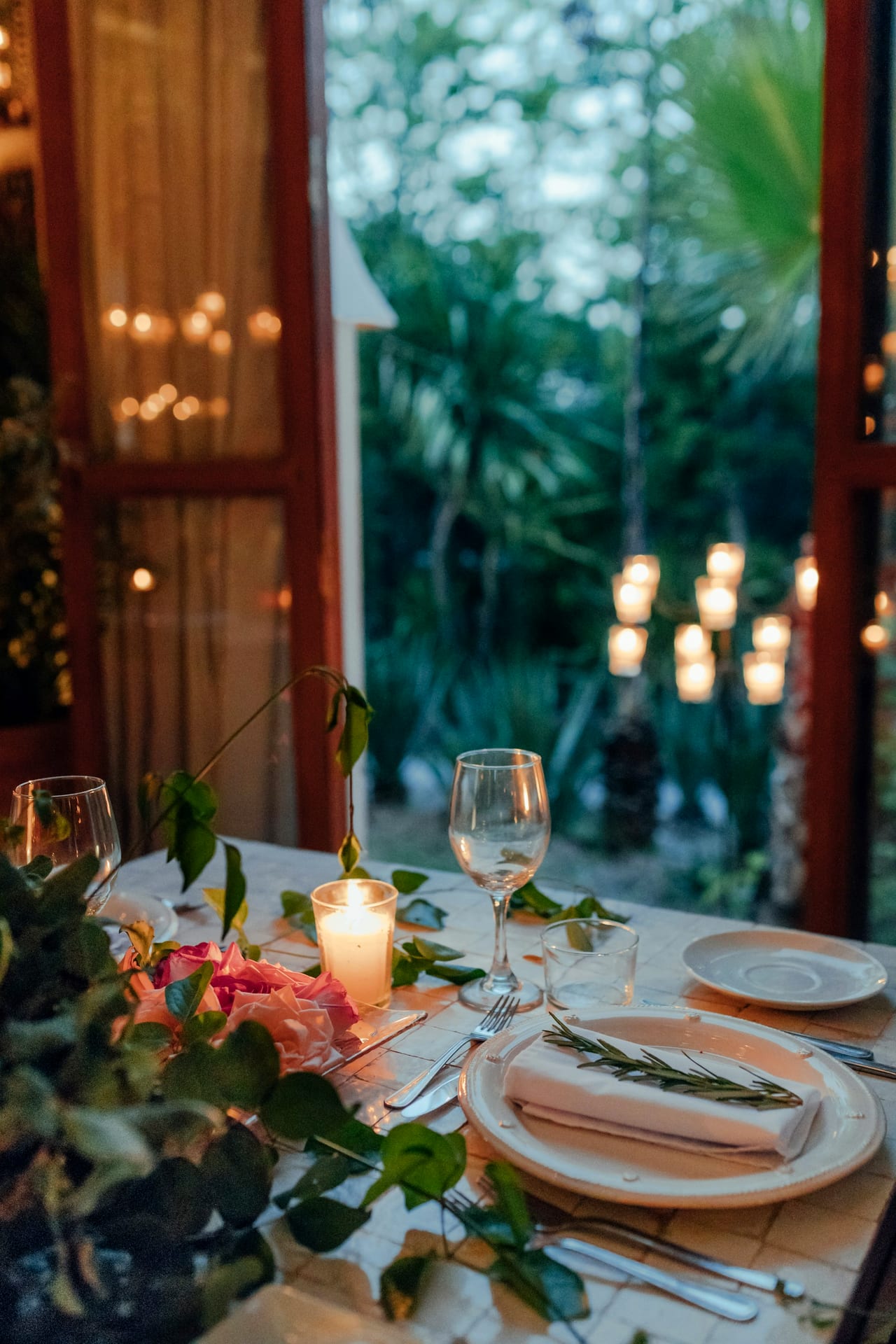 A table set for a festive dinner with candles and greenery