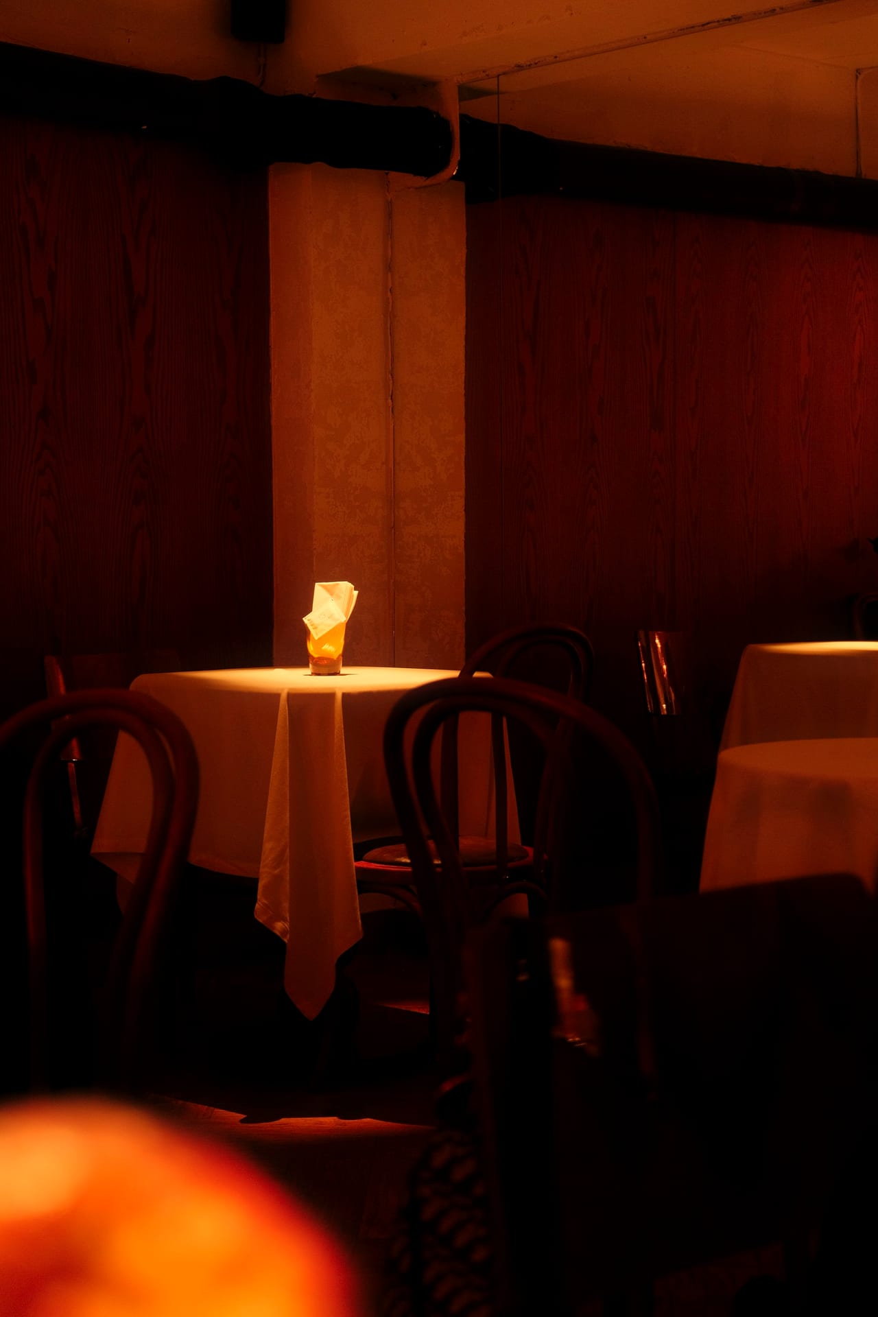 A dimly lit restaurant table set with a single candle