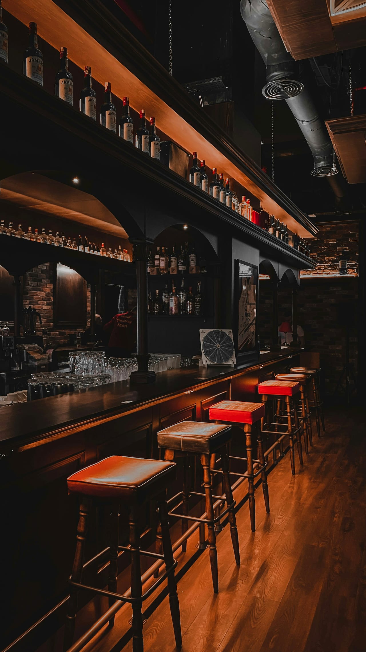 A bar with stools and shelves of glassware, before service