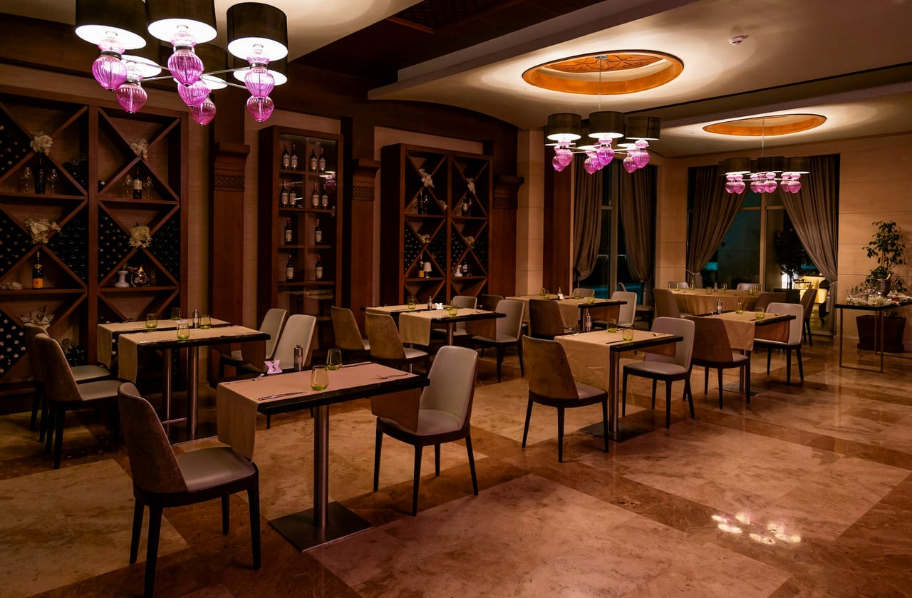 An elegant restaurant dining room set for service, warm low light