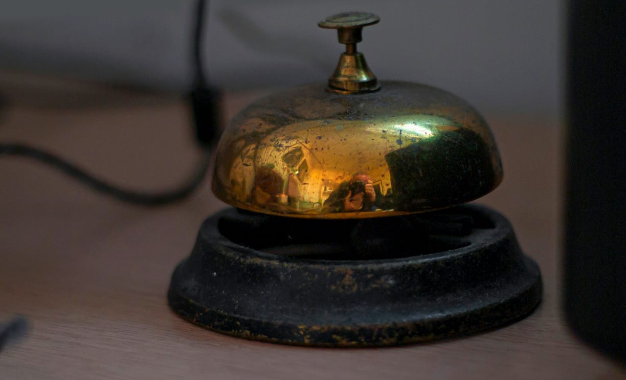 A brass service bell on a hotel reception desk