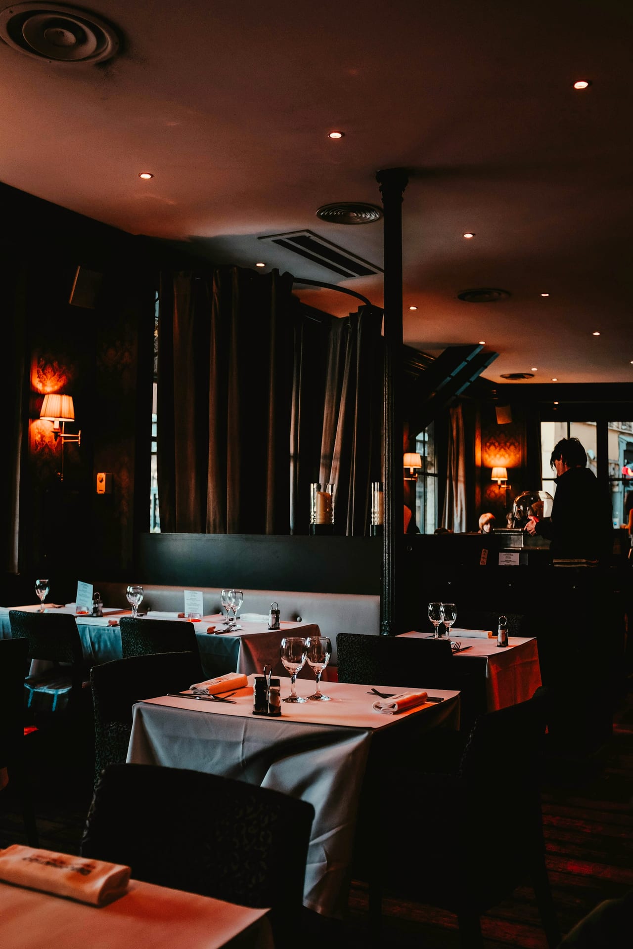 A warm dining room, tables set before service
